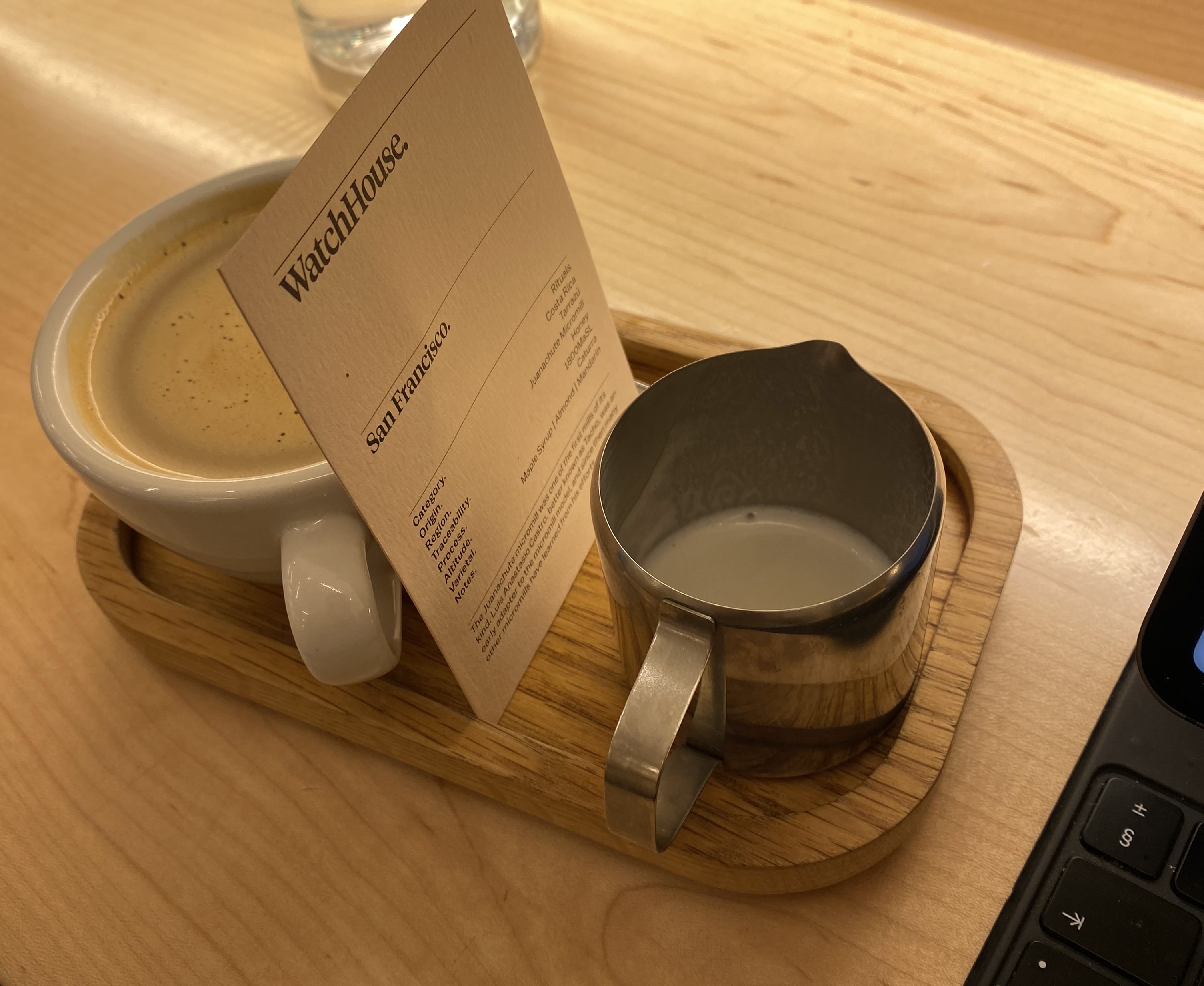 Flat white served on a tray with bean card at WatchHouse Marylebone